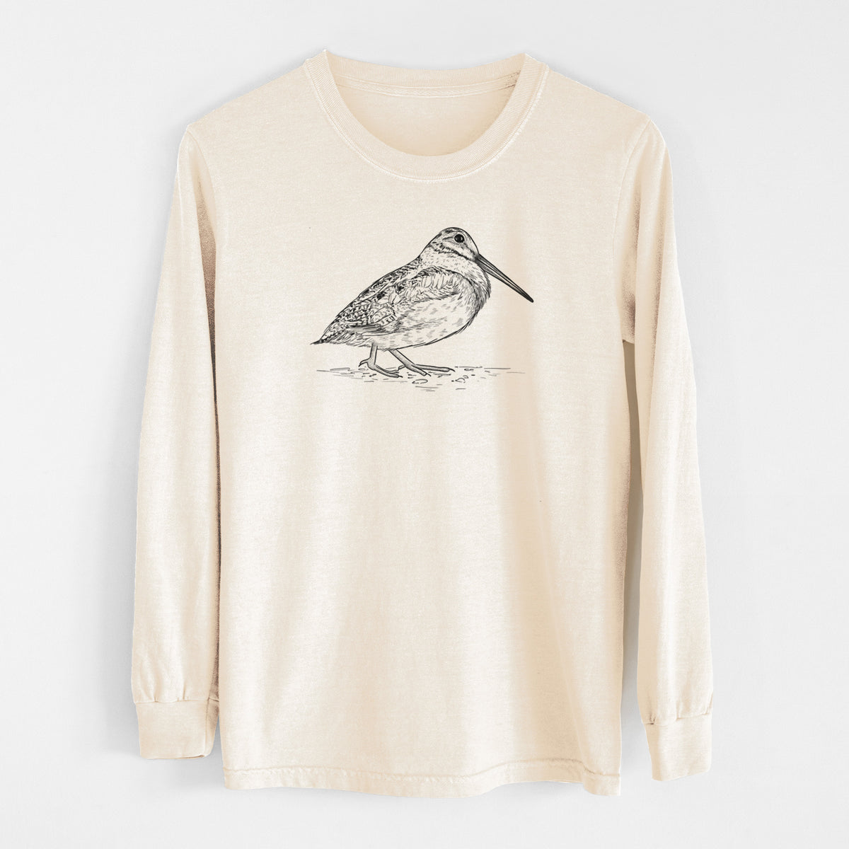 Ivory Comfort Colors long sleeve shirt laid flat, printed with a detailed black ink sketch of an American woodcock standing on the ground.