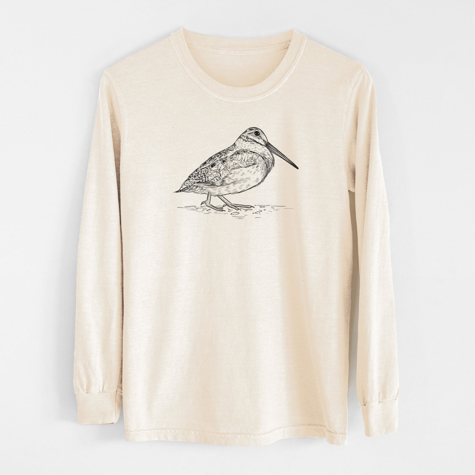 Ivory Comfort Colors long sleeve shirt laid flat, printed with a detailed black ink sketch of an American woodcock standing on the ground.