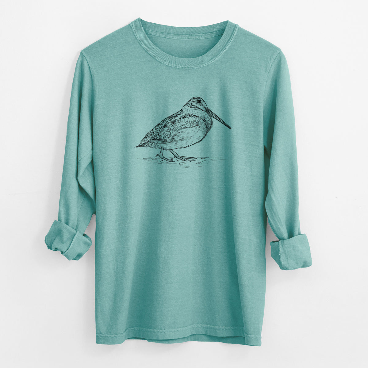 Reef green Comfort Colors long sleeve shirt laid flat with the cuffs rolled, printed with a detailed black ink sketch of an American woodcock standing on the ground.