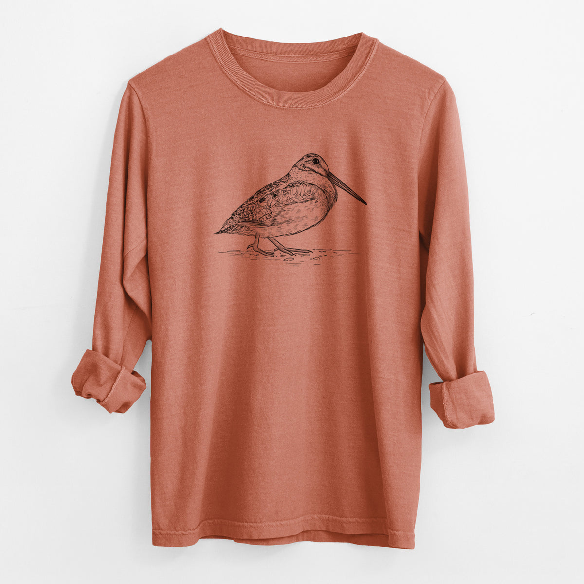 Yam burnt orange Comfort Colors long sleeve shirt laid flat with the cuffs rolled, printed with a detailed black ink sketch of an American woodcock standing on the ground.