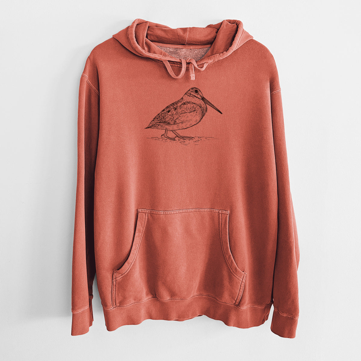 Amber orange pigment dyed hoodie laid flat, printed with a detailed black ink sketch of an American woodcock standing on the ground.