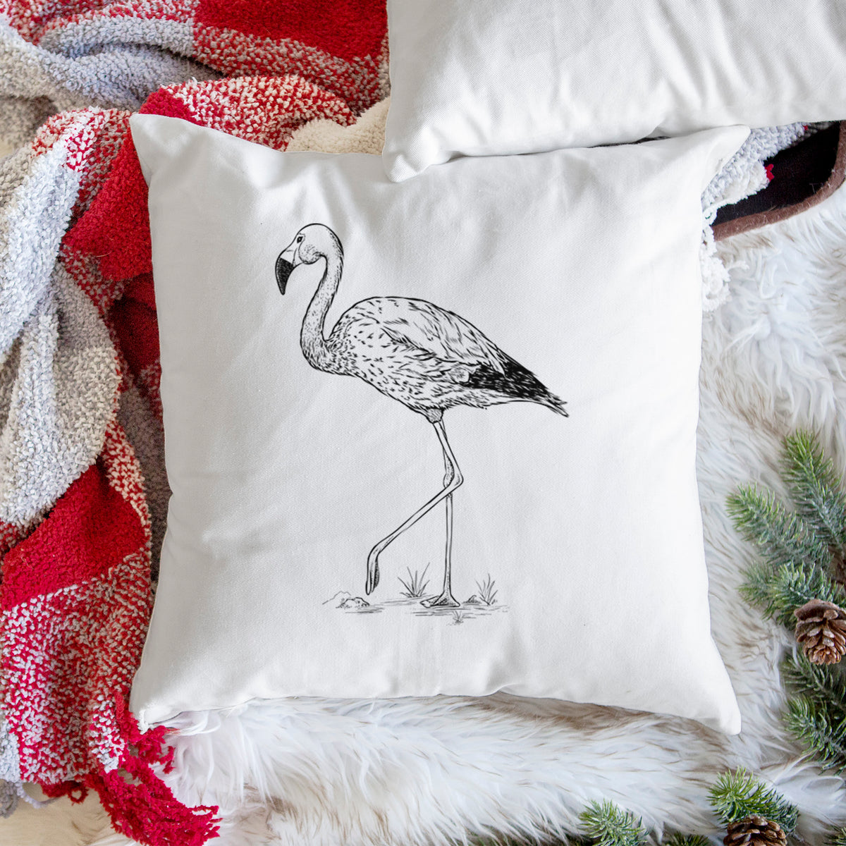White pillow cover printed with a black ink illustration of an Andean flamingo standing on one leg, on a woven chair.