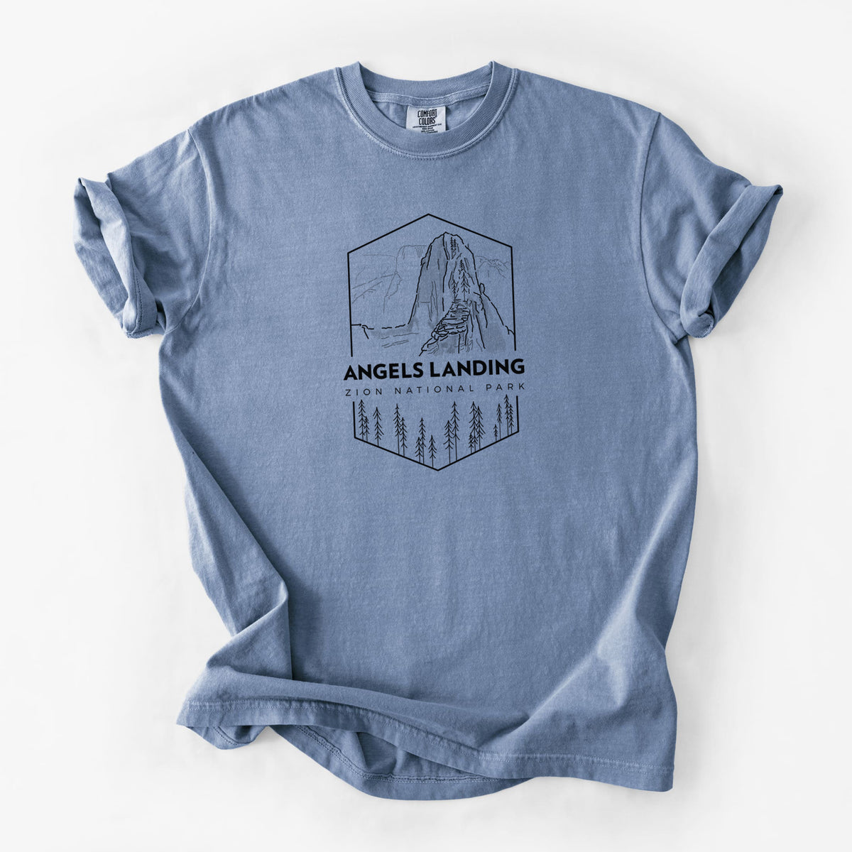 Blue jean Comfort Colors t-shirt laid flat, printed with a black line art badge of Angels Landing above pine trees, with the words Angels Landing, Zion National Park.