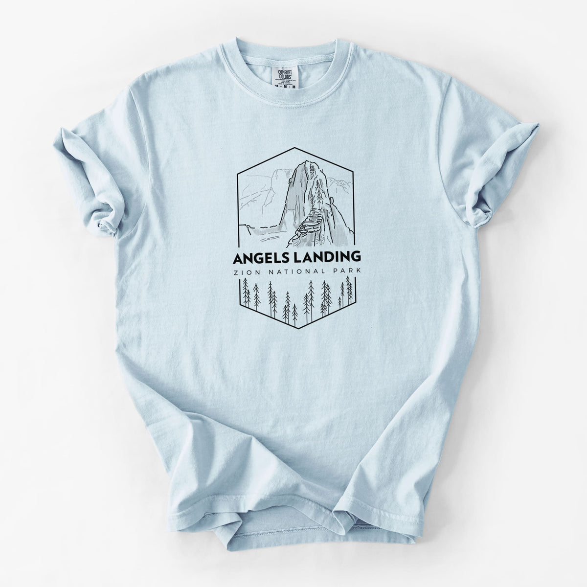 Chambray blue Comfort Colors t-shirt laid flat, printed with a black line art badge of Angels Landing above pine trees, with the words Angels Landing, Zion National Park.