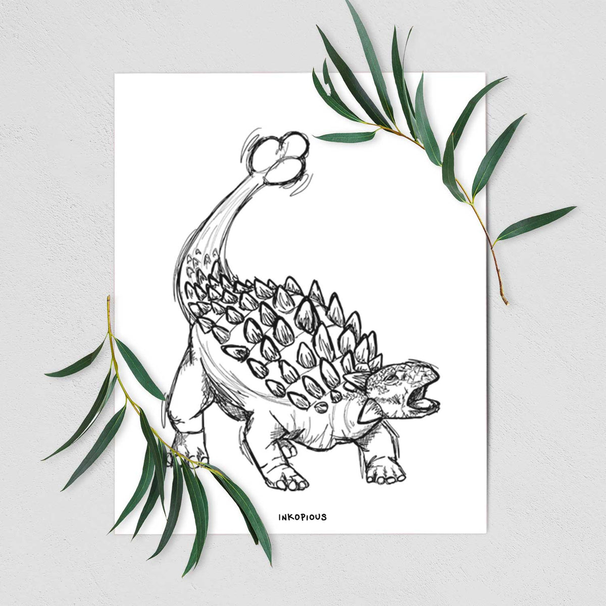 Art print of a black ink illustration of an Ankylosaurus with its club tail raised, shown with eucalyptus leaves.
