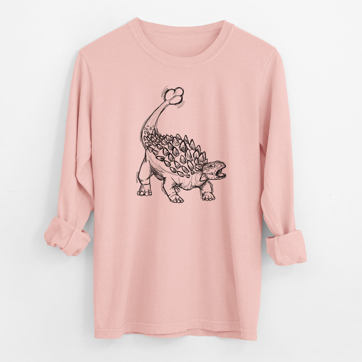 Peachy Comfort Colors long sleeve shirt laid flat with the cuffs rolled, printed with a black ink illustration of an Ankylosaurus with its club tail raised.