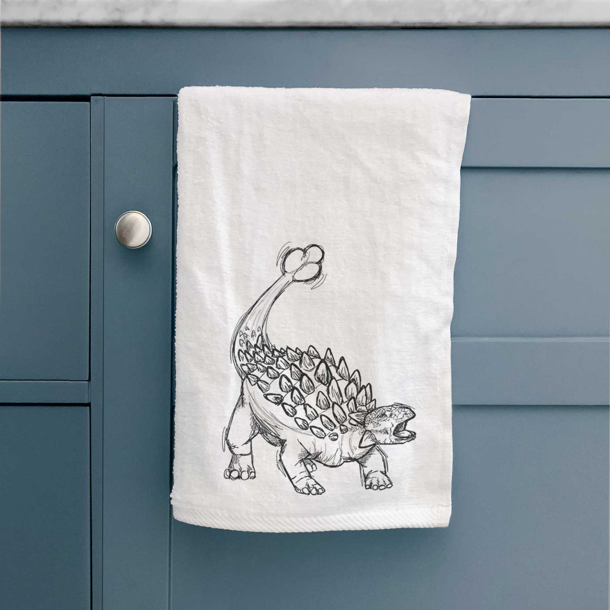 White hand towel printed with a black ink illustration of an Ankylosaurus with its club tail raised.