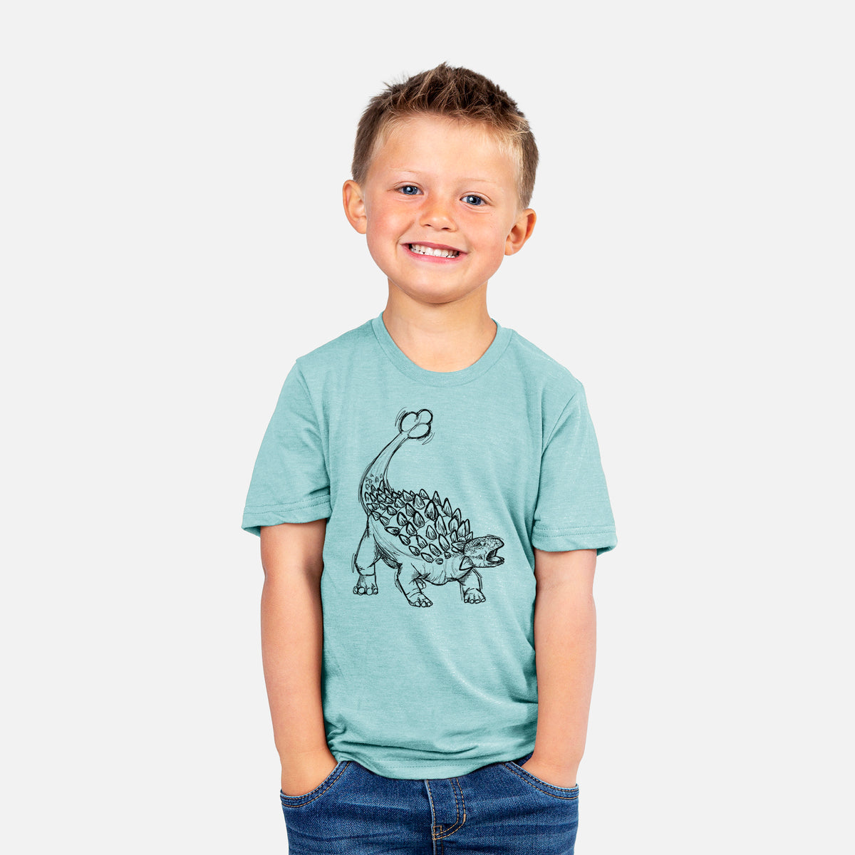 Smiling boy wearing a youth t-shirt printed with a black ink illustration of an Ankylosaurus with its club tail raised.