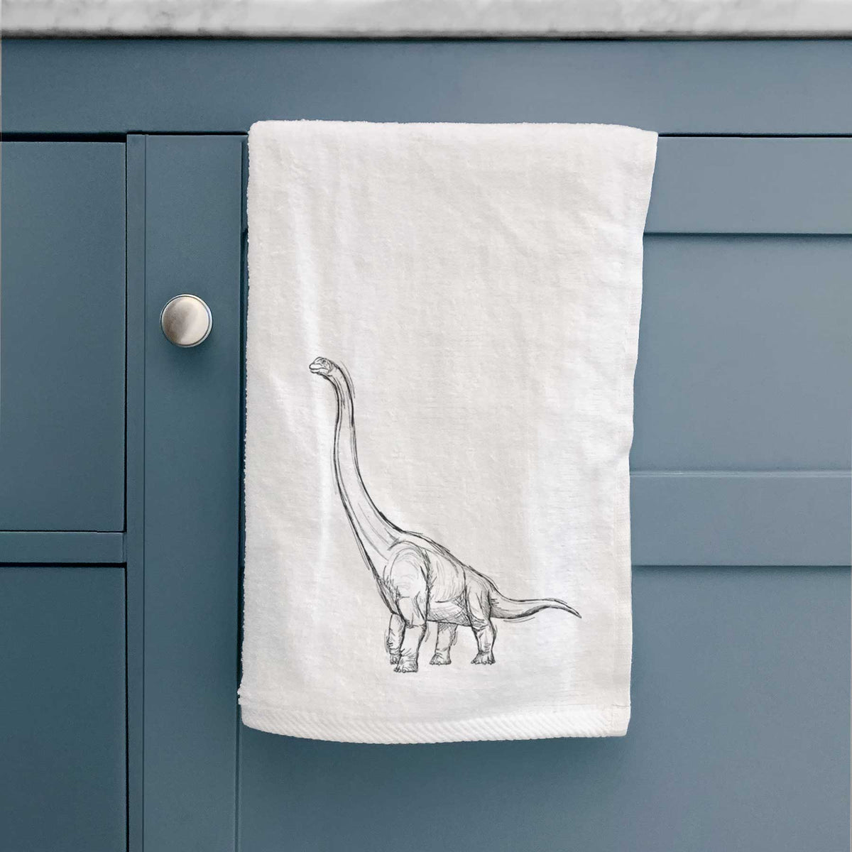White hand towel printed with a black ink illustration of a long-necked Apatosaurus walking.