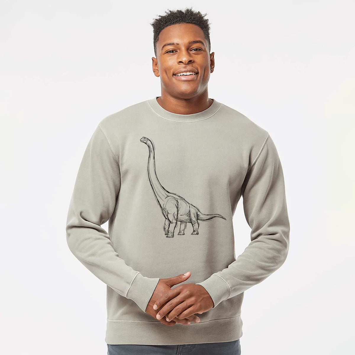 Model wearing a cement grey pigment dyed crewneck sweatshirt printed with a black ink illustration of a long-necked Apatosaurus walking.