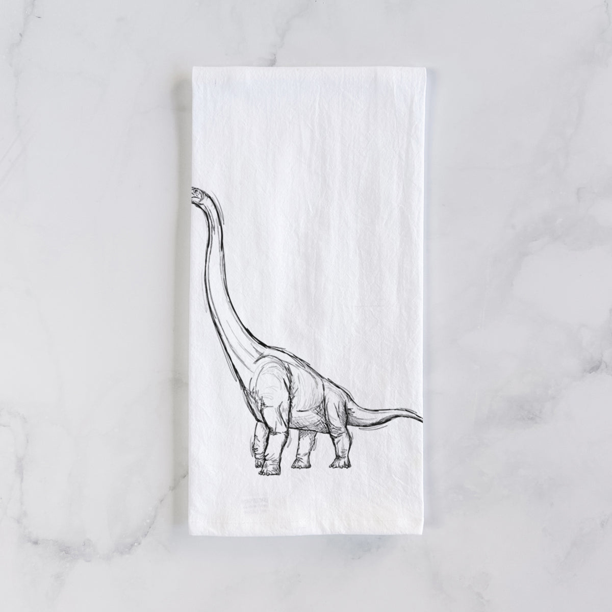 White cotton tea towel laid flat on marble, printed with a black ink illustration of a long-necked Apatosaurus walking.