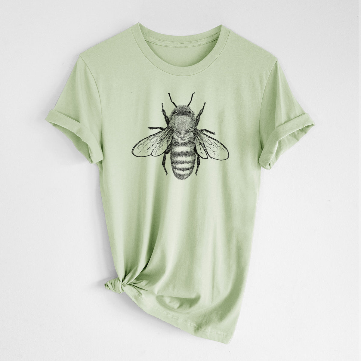 Spring green lightweight cotton t-shirt laid flat with the sleeves rolled, printed with a detailed black ink illustration of a honey bee with its wings spread, seen from above.