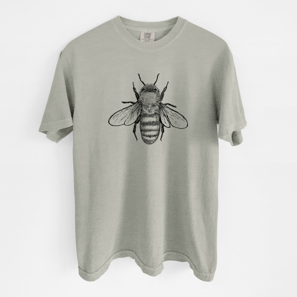 Sandstone beige Comfort Colors t-shirt laid flat, printed with a detailed black ink illustration of a honey bee with its wings spread, seen from above.