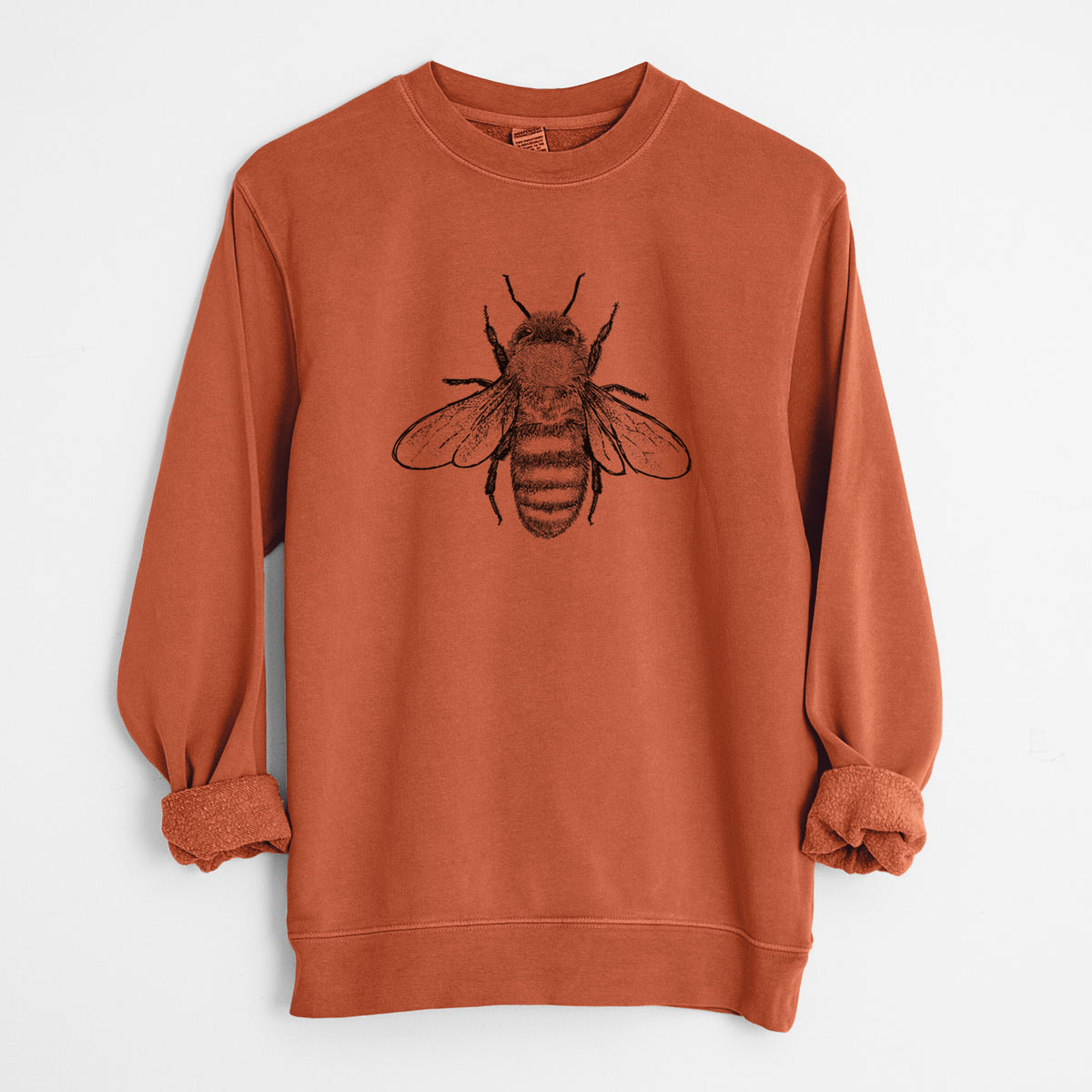 Amber orange pigment dyed crewneck sweatshirt laid flat with the sleeves rolled, printed with a detailed black ink illustration of a honey bee with its wings spread, seen from above.