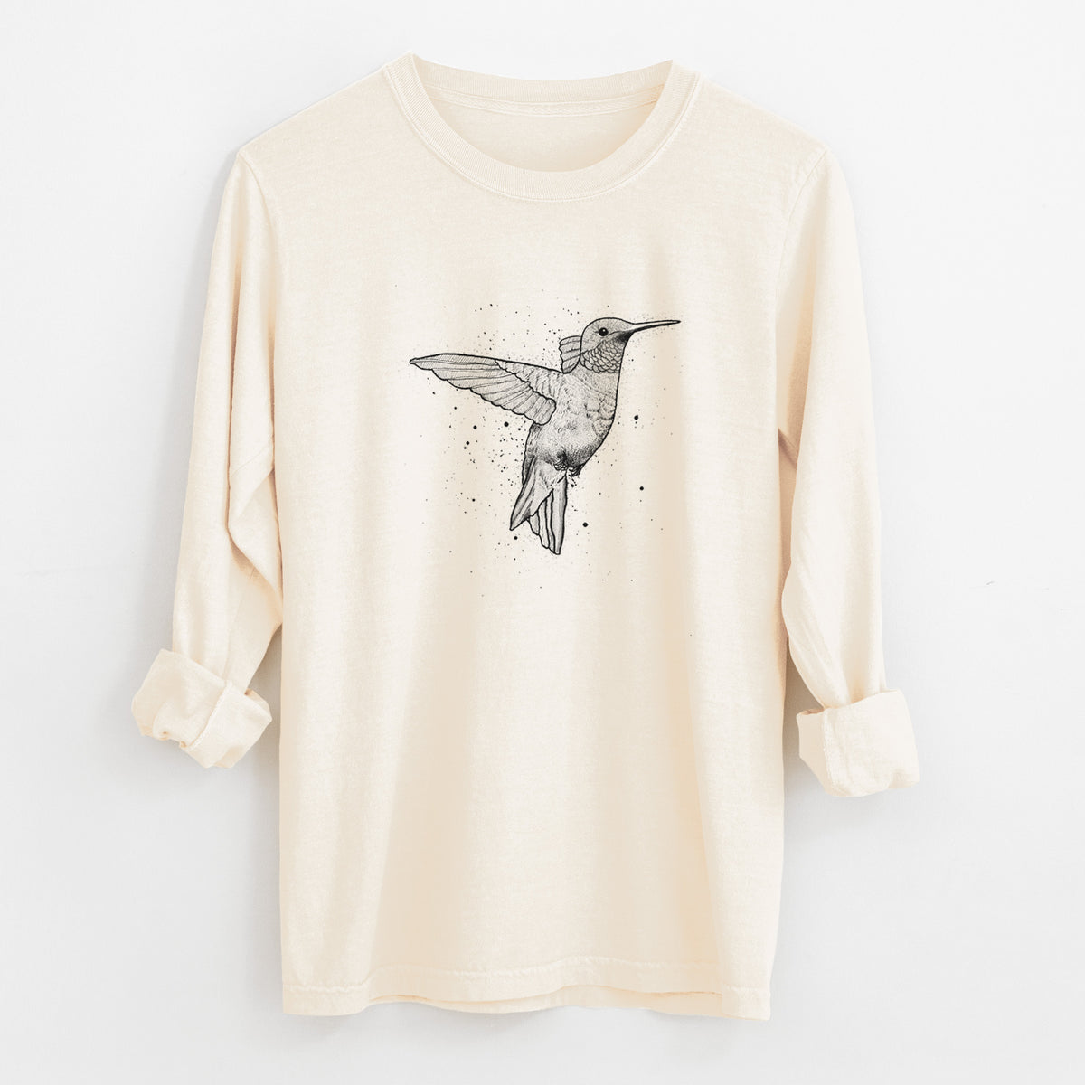 Ivory Comfort Colors long sleeve shirt laid flat with the cuffs rolled, printed with a black ink sketch of a ruby-throated hummingbird hovering with its wings raised.