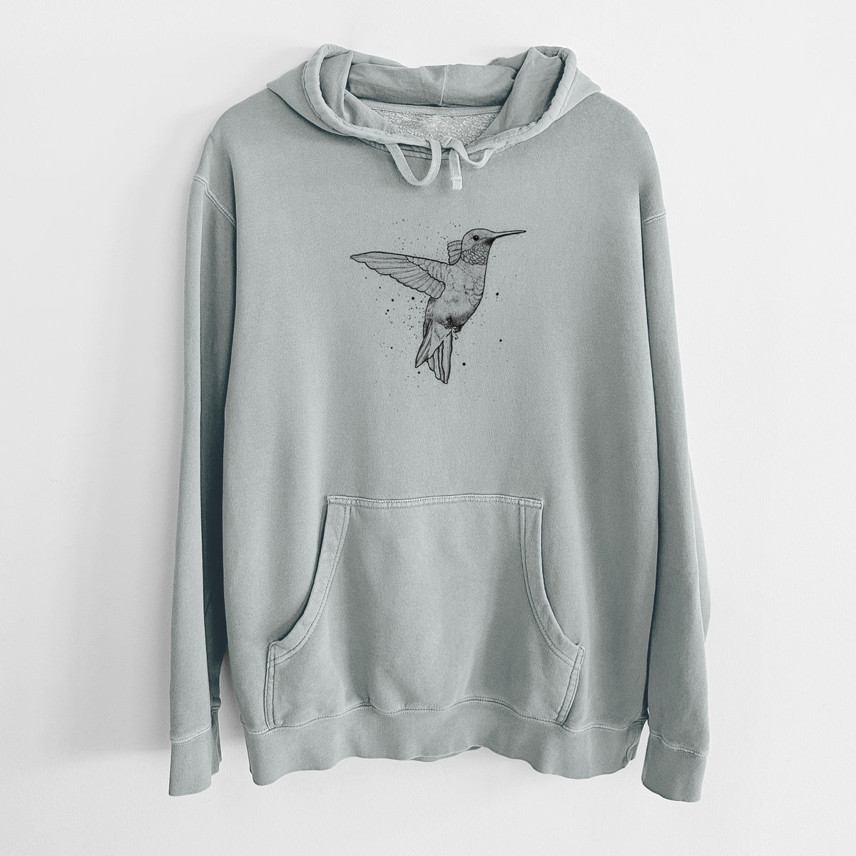 Sage green pigment dyed hoodie laid flat, printed with a black ink sketch of a ruby-throated hummingbird hovering with its wings raised.