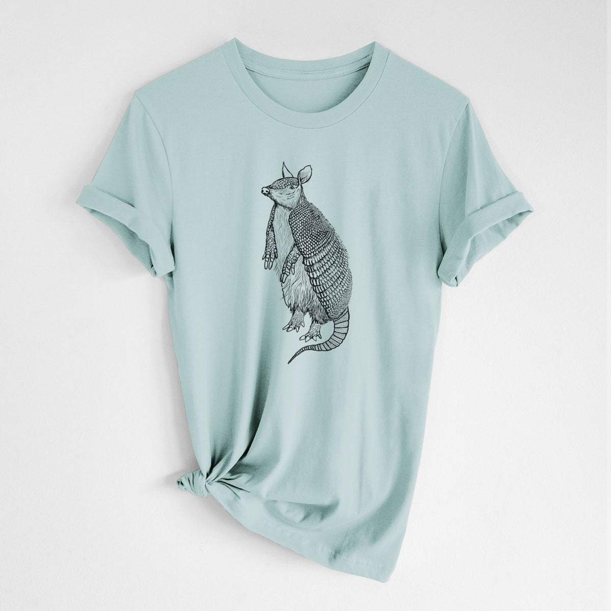 Dusty blue lightweight cotton t-shirt laid flat with the sleeves rolled, printed with a black ink illustration of a nine-banded armadillo standing upright.