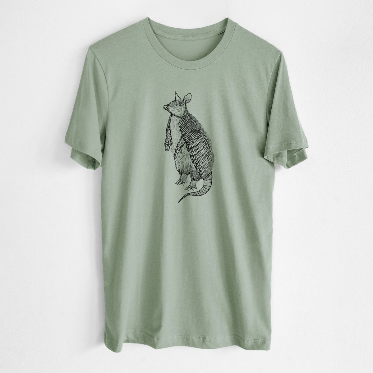 Sage green lightweight cotton t-shirt laid flat, printed with a black ink illustration of a nine-banded armadillo standing upright.