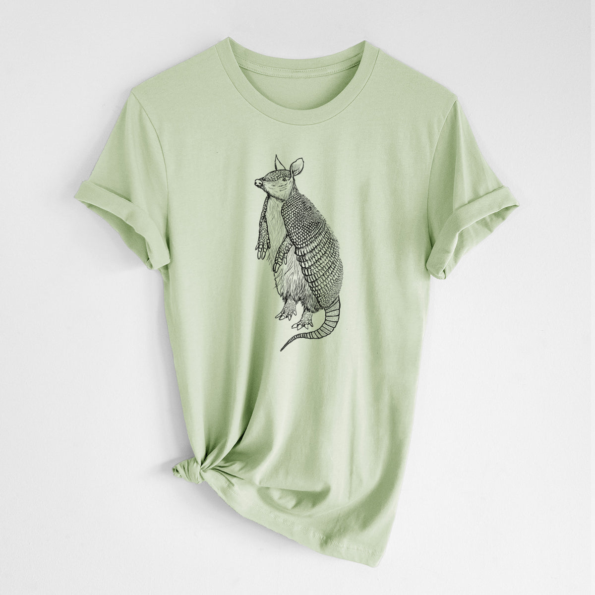 Spring green lightweight cotton t-shirt laid flat with the sleeves rolled, printed with a black ink illustration of a nine-banded armadillo standing upright.