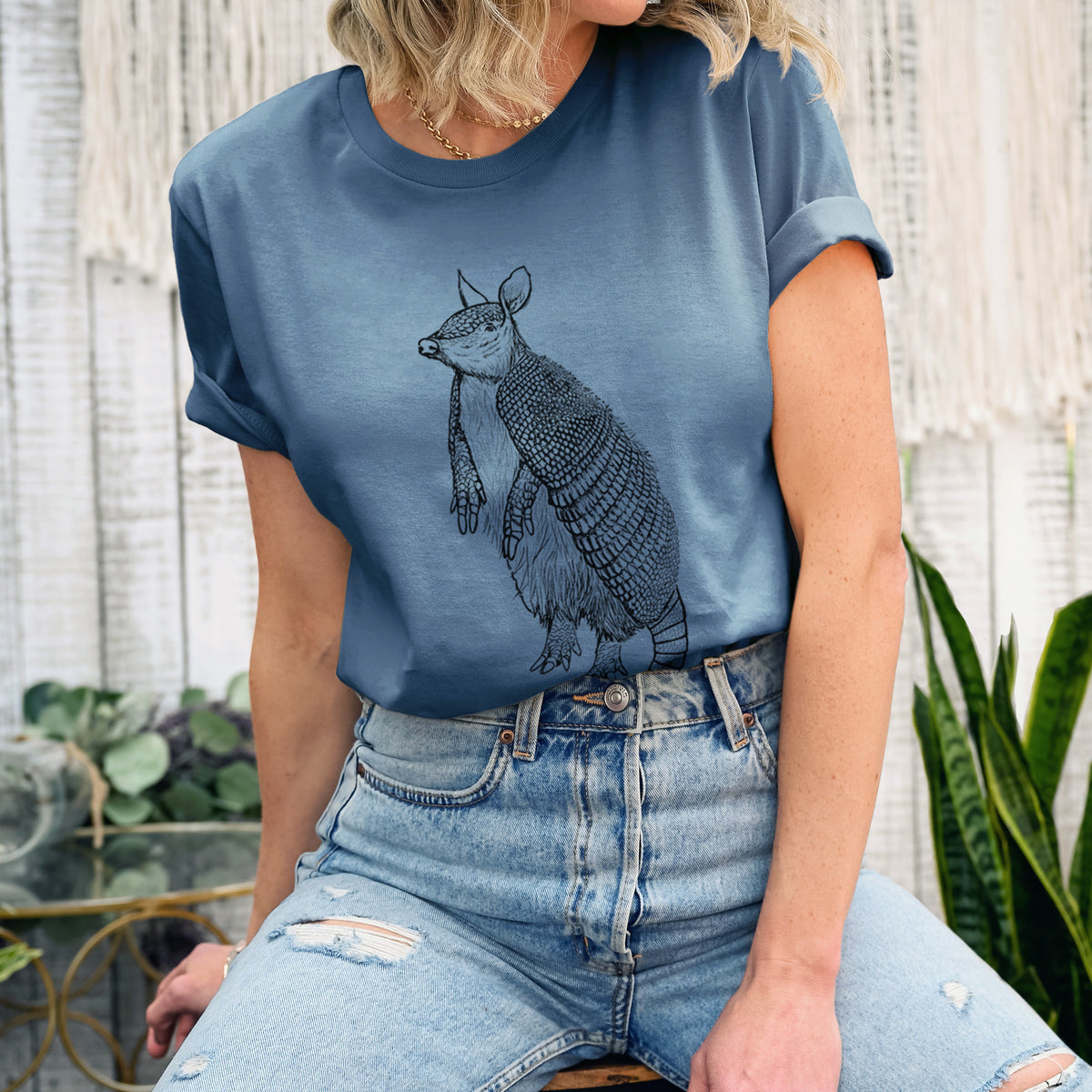 Woman wearing a steel blue lightweight cotton t-shirt printed with a black ink illustration of a nine-banded armadillo standing upright.