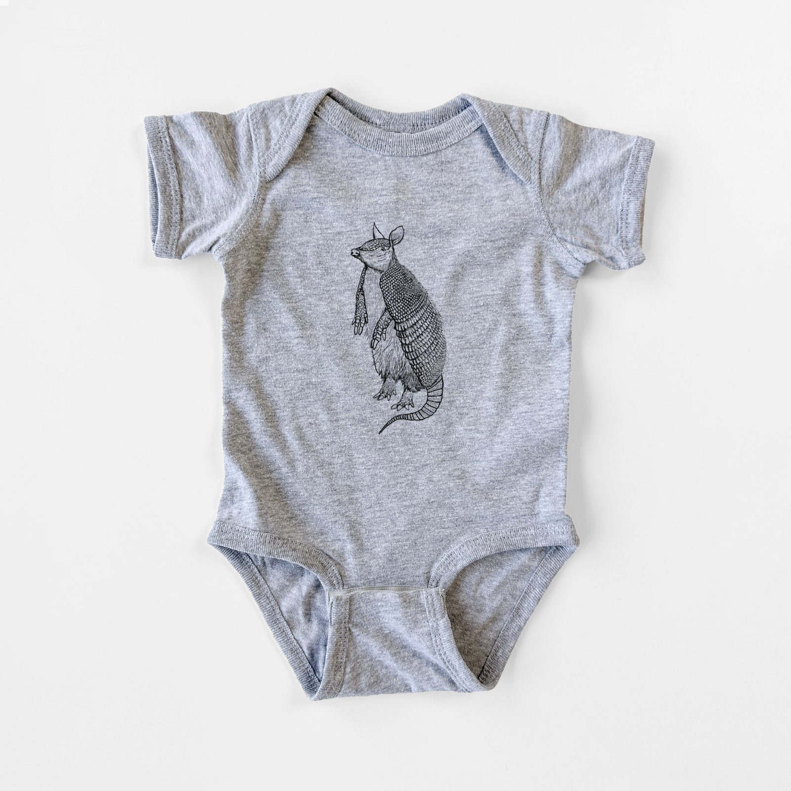 Grey baby bodysuit laid flat, printed with a black ink illustration of a nine-banded armadillo standing upright.