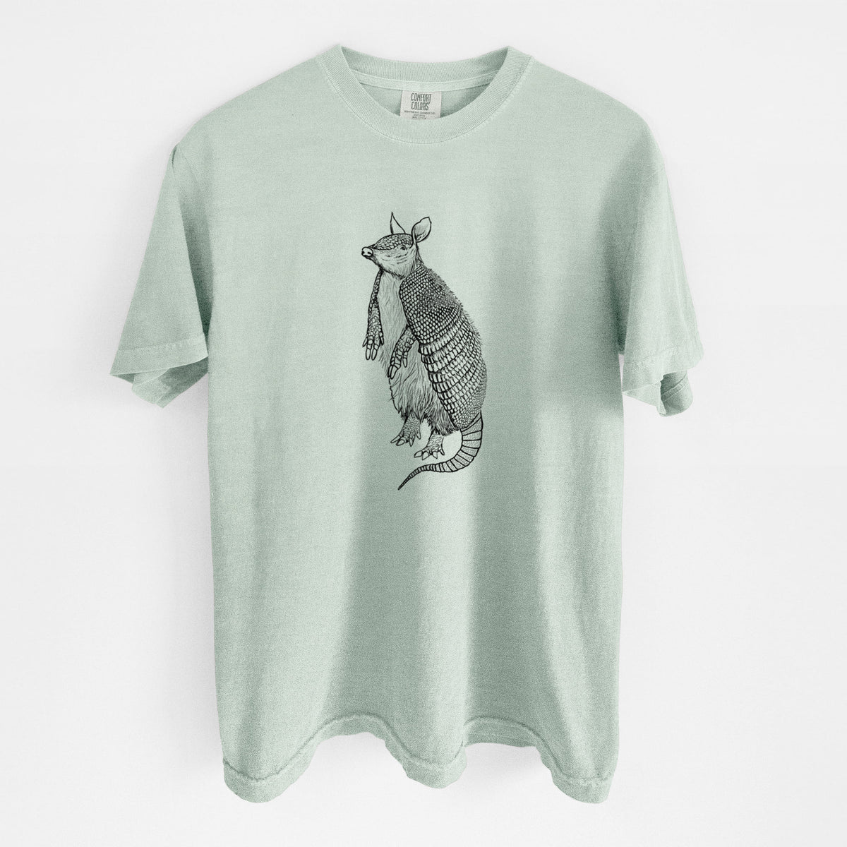 Bay green Comfort Colors t-shirt laid flat, printed with a black ink illustration of a nine-banded armadillo standing upright.