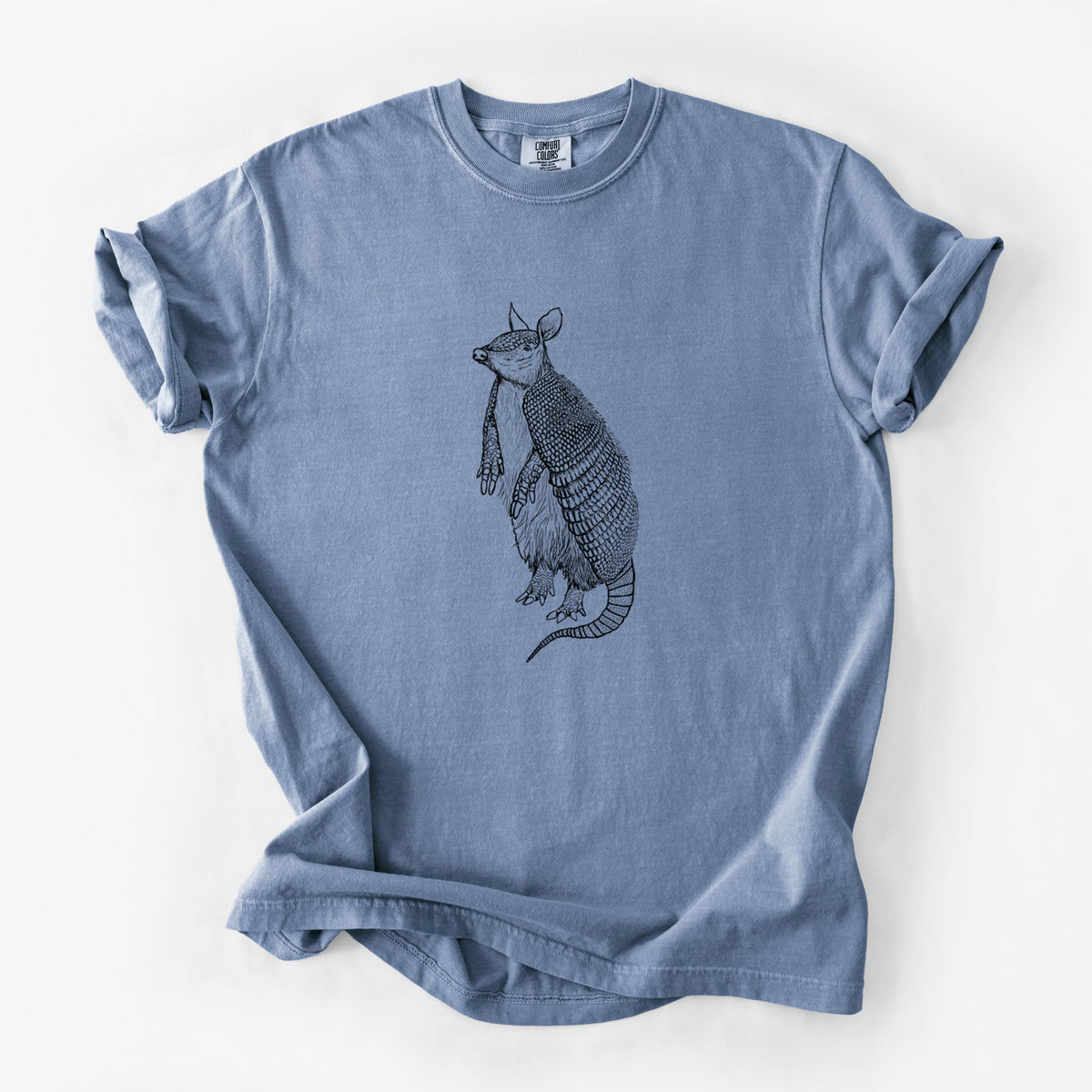 Blue jean Comfort Colors t-shirt laid flat, printed with a black ink illustration of a nine-banded armadillo standing upright.