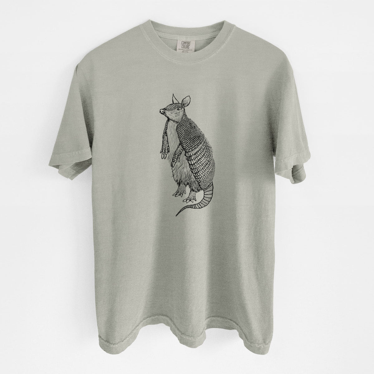 Sandstone beige Comfort Colors t-shirt laid flat, printed with a black ink illustration of a nine-banded armadillo standing upright.