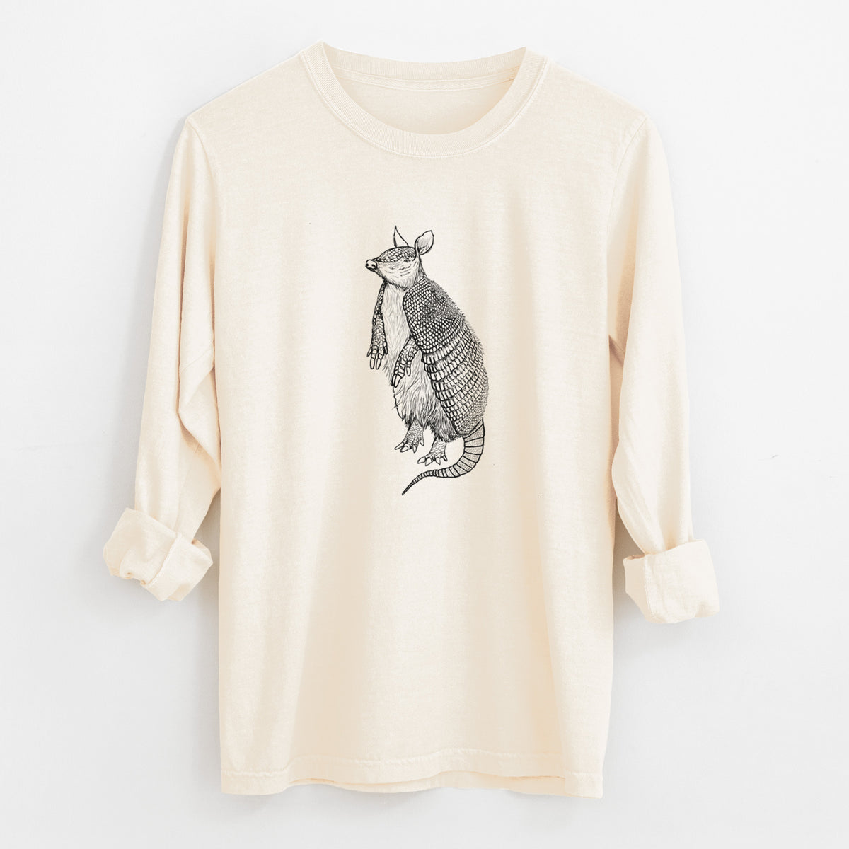 Ivory Comfort Colors long sleeve shirt laid flat with the cuffs rolled, printed with a black ink illustration of a nine-banded armadillo standing upright.