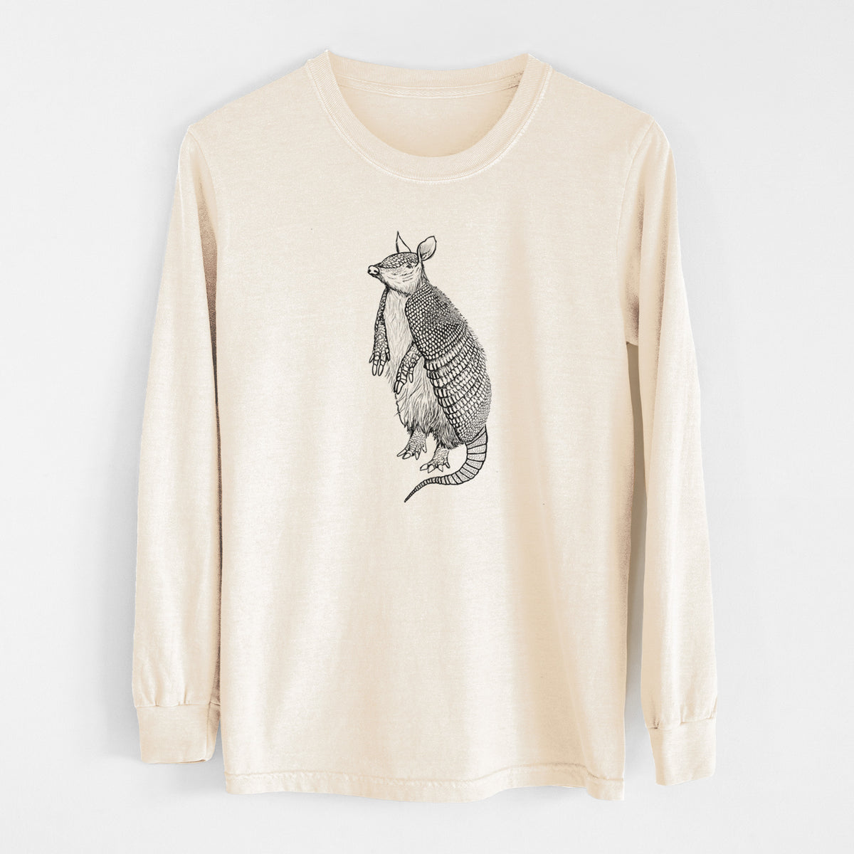 Ivory Comfort Colors long sleeve shirt laid flat, printed with a black ink illustration of a nine-banded armadillo standing upright.
