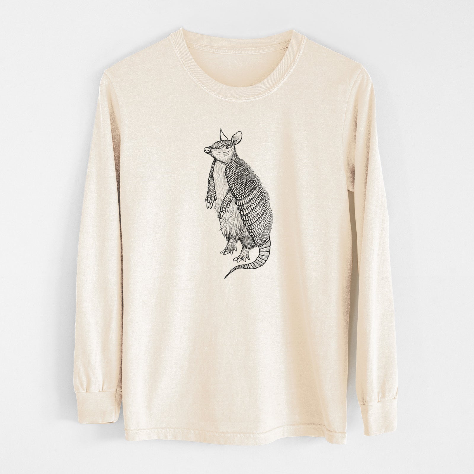 Ivory Comfort Colors long sleeve shirt laid flat, printed with a black ink illustration of a nine-banded armadillo standing upright.