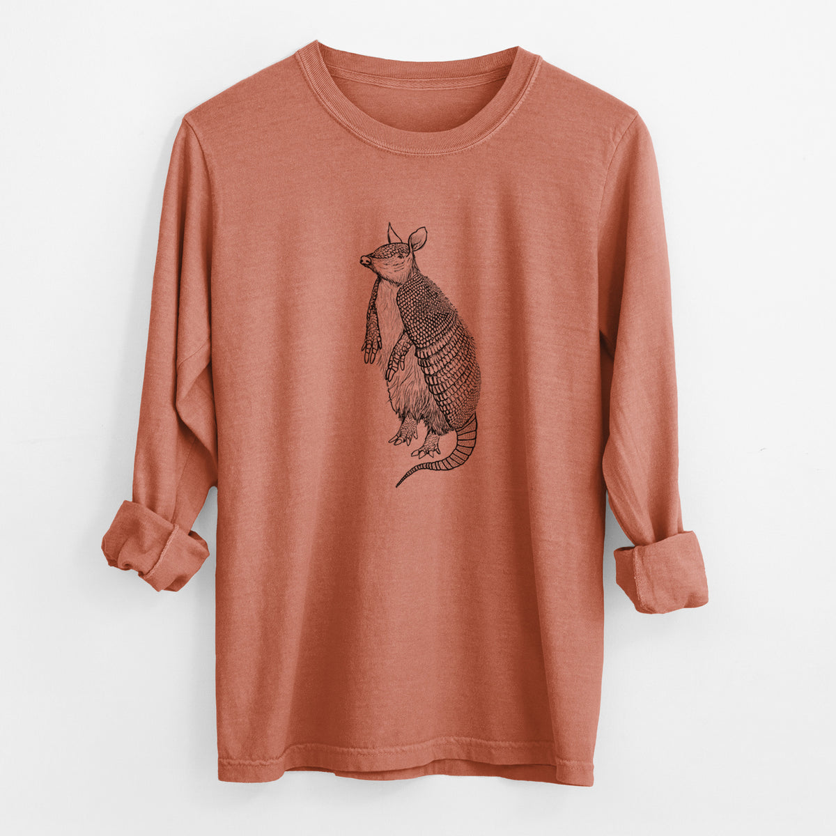 Yam burnt orange Comfort Colors long sleeve shirt laid flat with the cuffs rolled, printed with a black ink illustration of a nine-banded armadillo standing upright.
