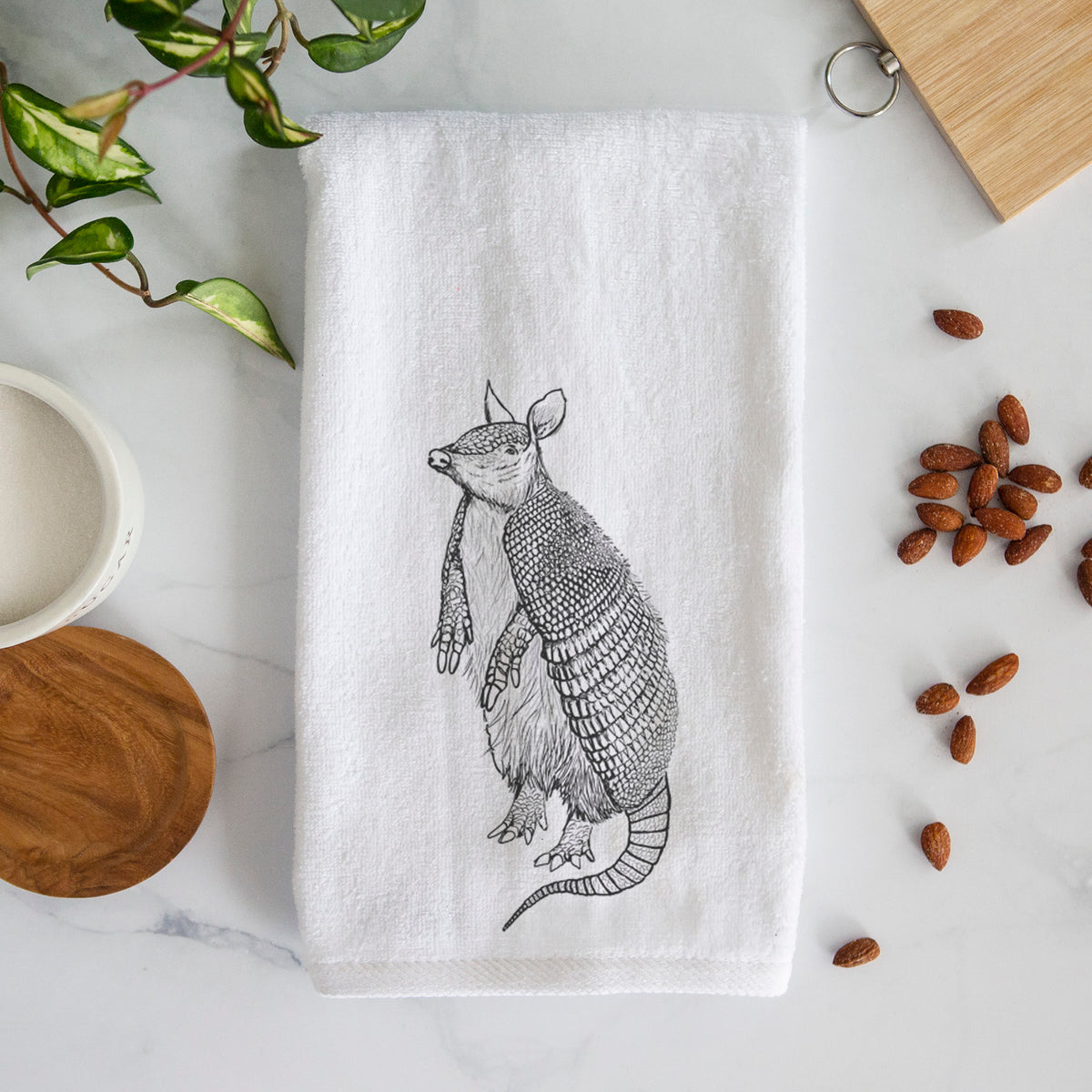 White hand towel printed with a black ink illustration of a nine-banded armadillo standing upright.