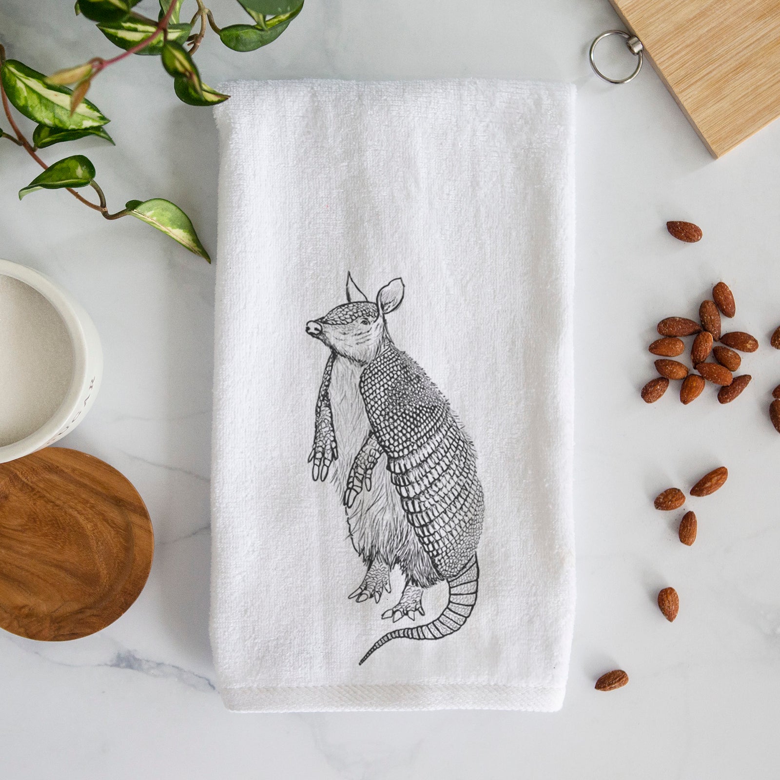 White hand towel printed with a black ink illustration of a nine-banded armadillo standing upright.