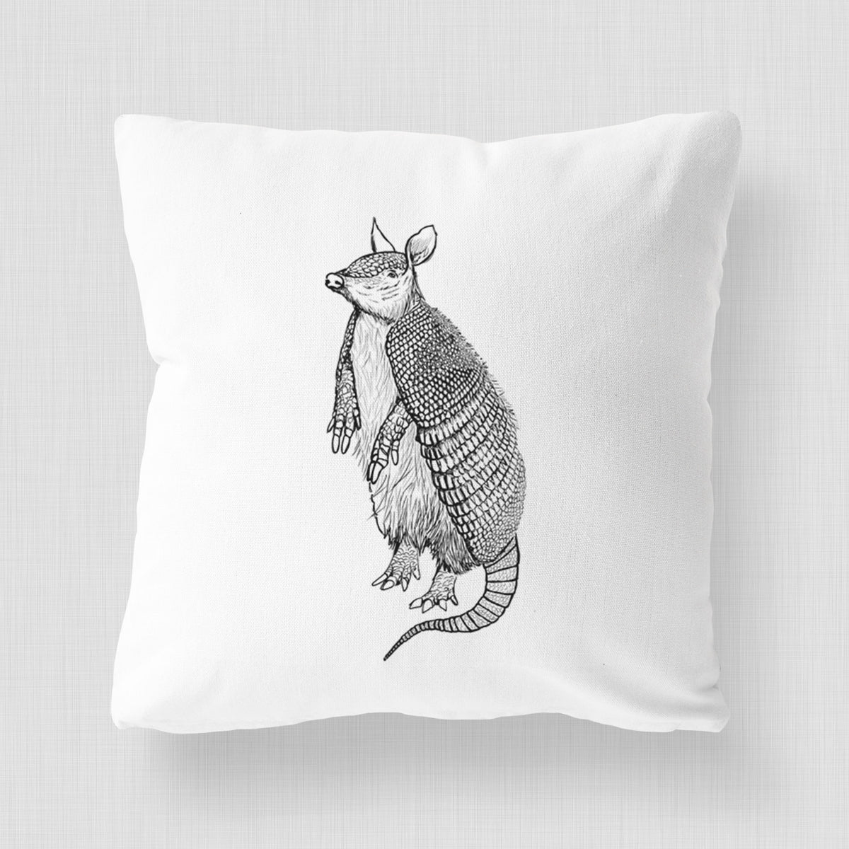 White pillow cover printed with a black ink illustration of a nine-banded armadillo standing upright.