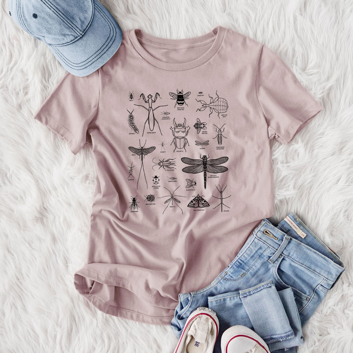 Women's relaxed fit cotton t-shirt printed with a chart of black ink insect and arthropod illustrations, including dragonflies, beetles, spiders and bees, styled flat on a white faux fur rug with jeans.