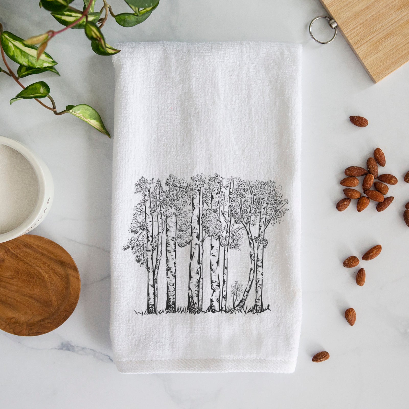 White hand towel printed with a black ink illustration of a grove of aspen trees.