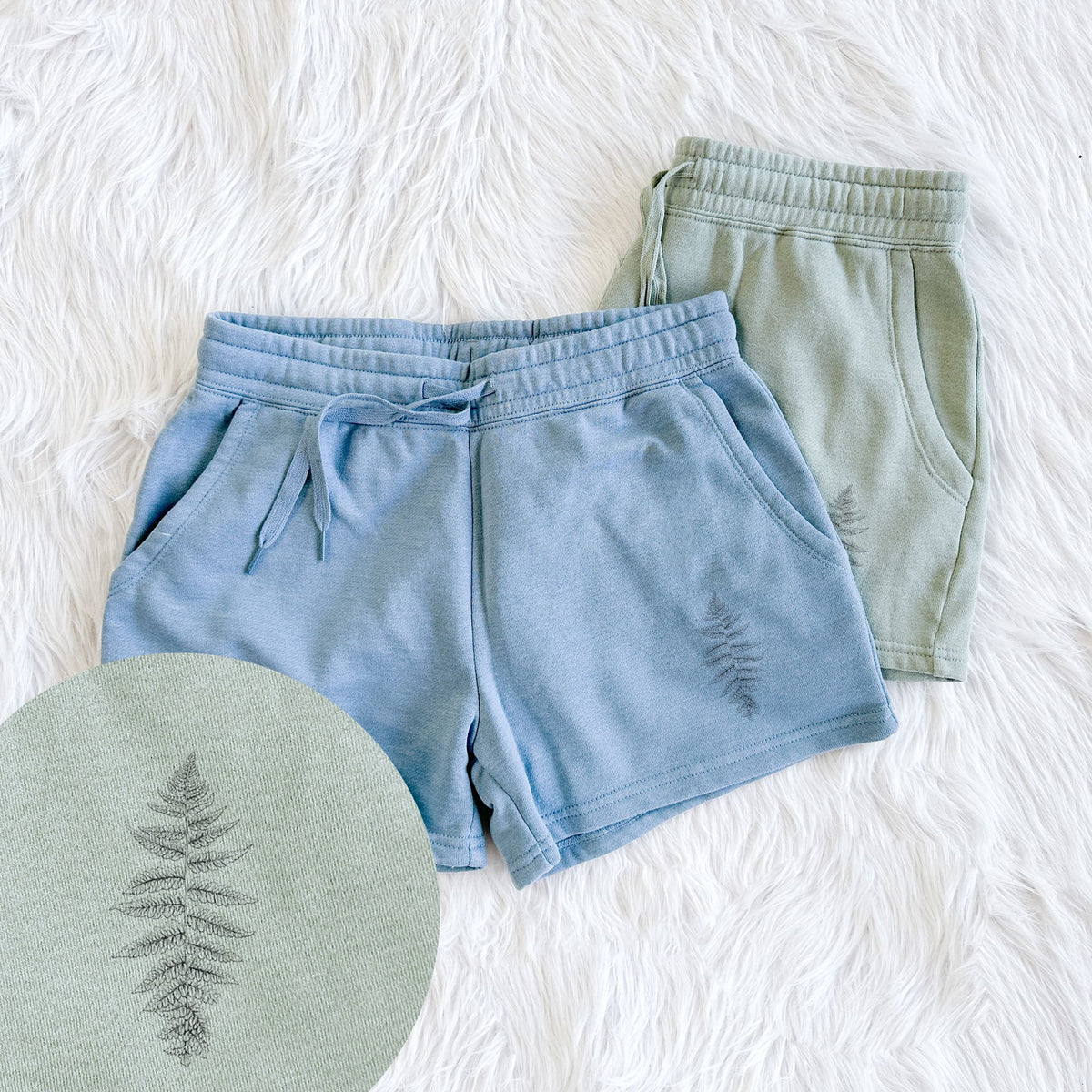 Two pairs of Cali Wave shorts in different colors printed with a black ink illustration of a lady fern frond, with a close-up of the print.