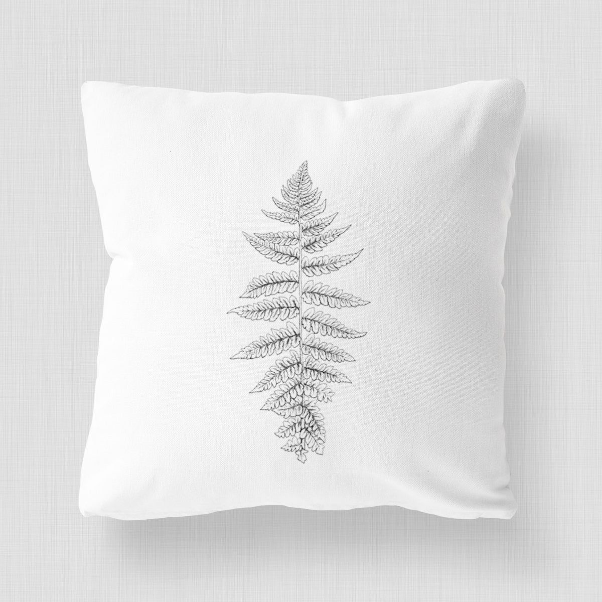 White pillow cover printed with a black ink illustration of a lady fern frond.