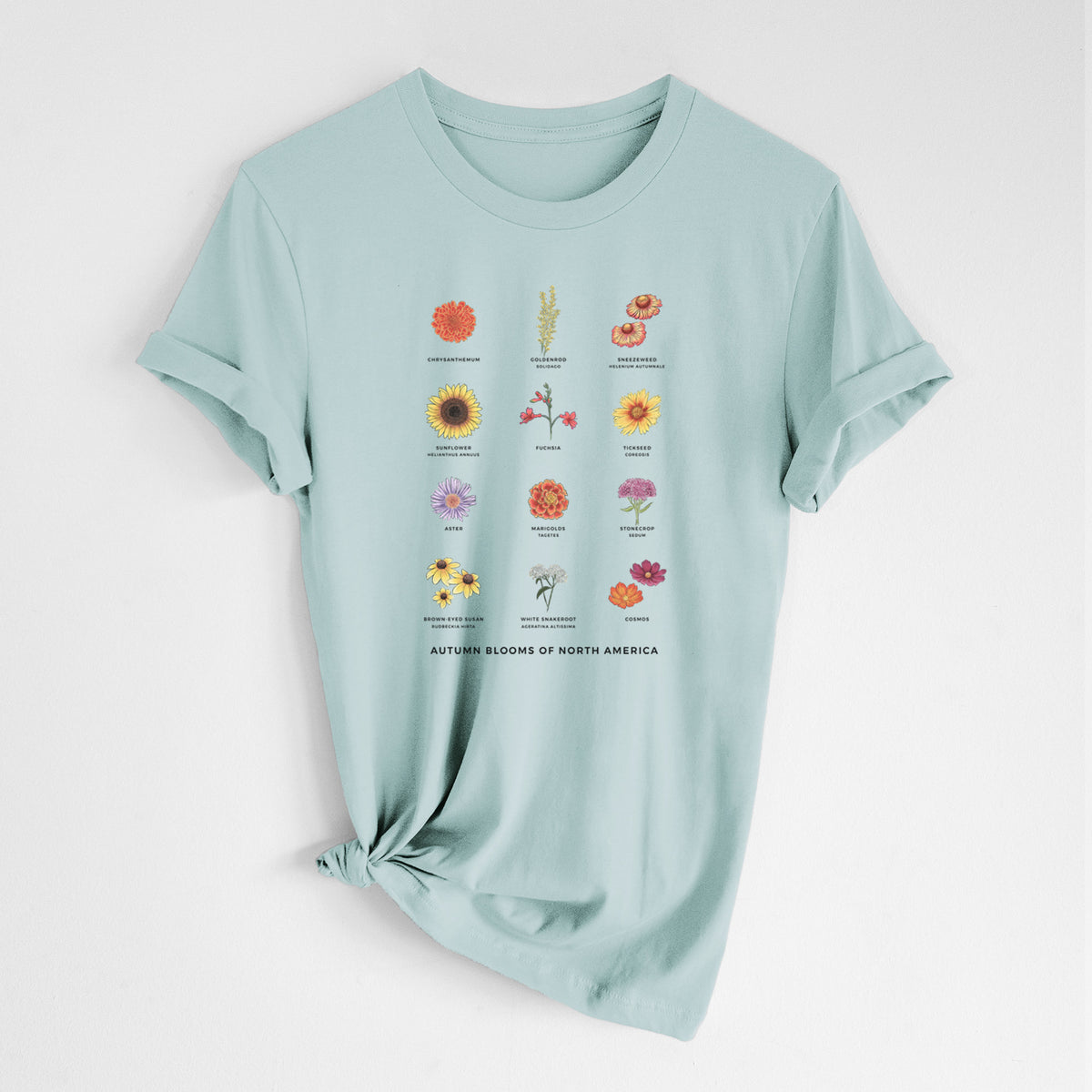 Dusty blue lightweight cotton t-shirt laid flat with the sleeves rolled, printed with a full-color chart of autumn flowers, each labeled with its name.