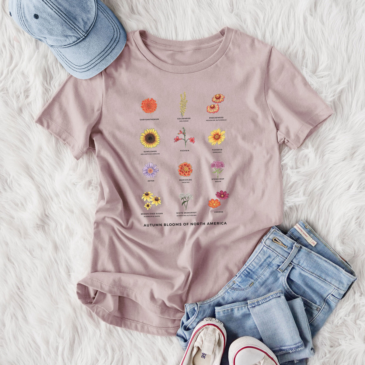 Women's relaxed fit cotton t-shirt printed with a full-color chart of autumn flowers, each labeled with its name, styled flat on a white faux fur rug with jeans.