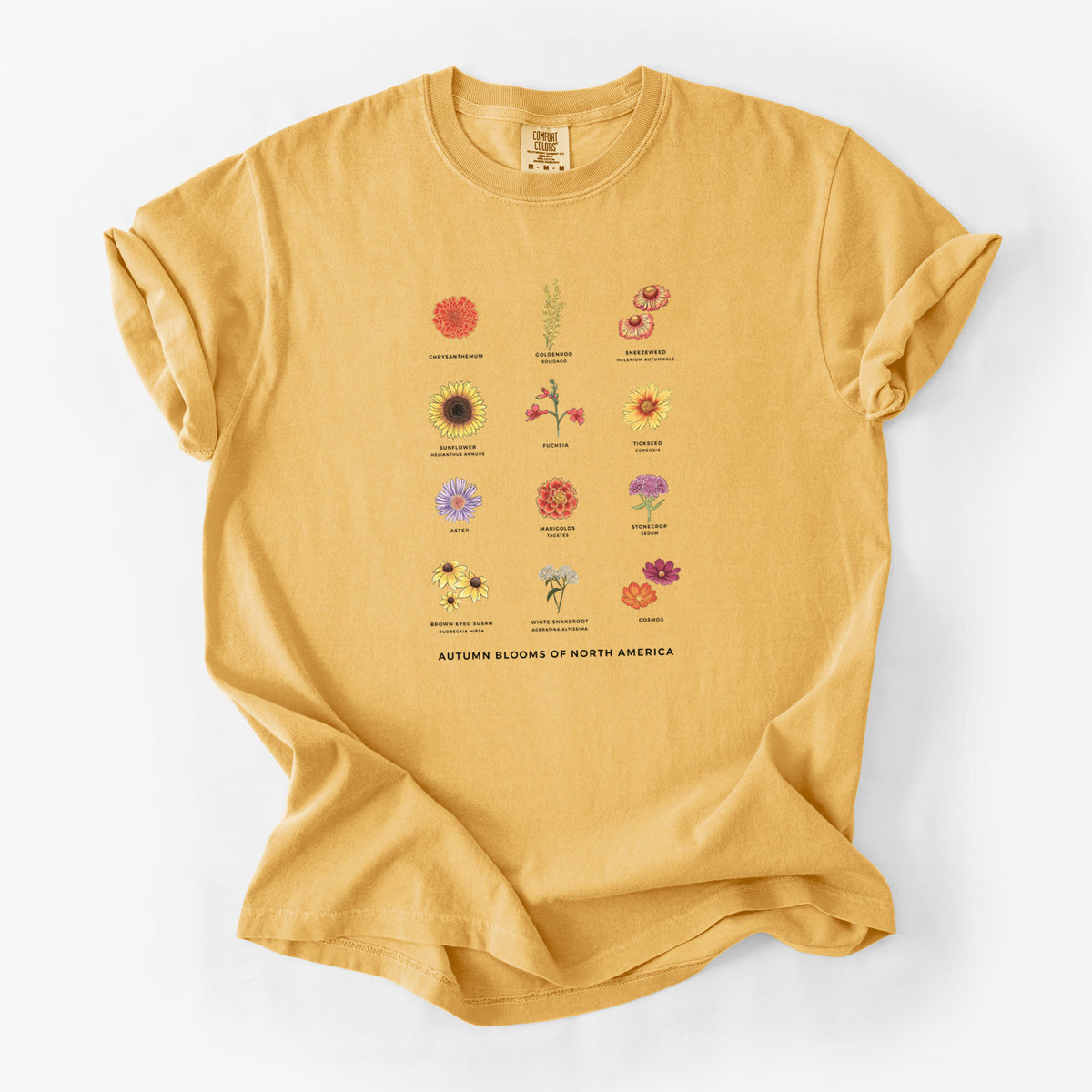 Golden wheat yellow Comfort Colors t-shirt laid flat, printed with a full-color chart of autumn flowers, each labeled with its name.