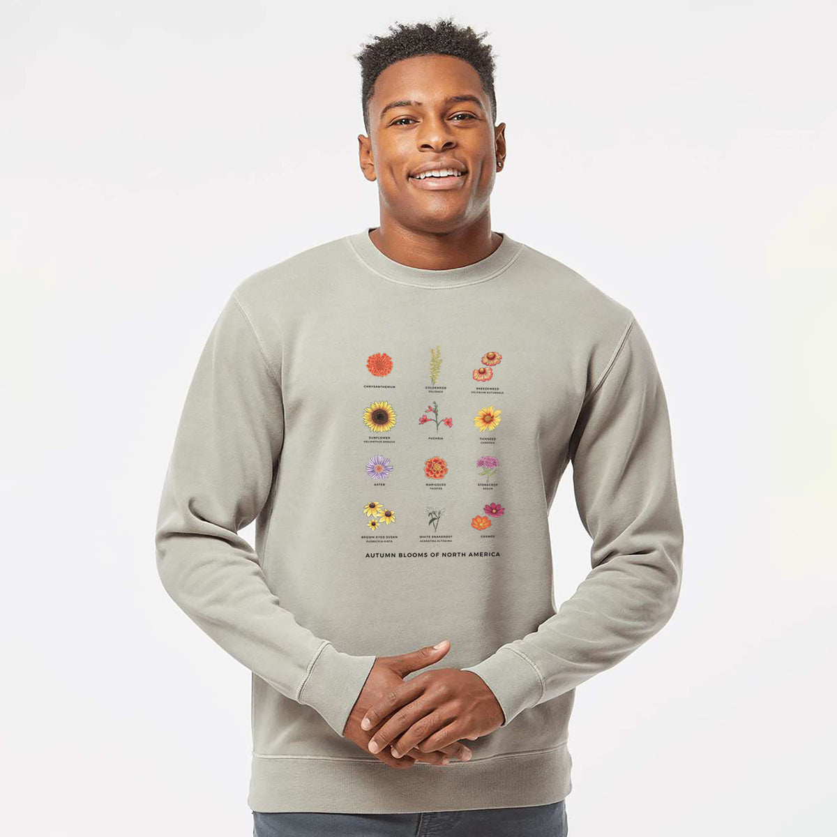 Model wearing a cement grey pigment dyed crewneck sweatshirt printed with a full-color chart of autumn flowers, each labeled with its name.