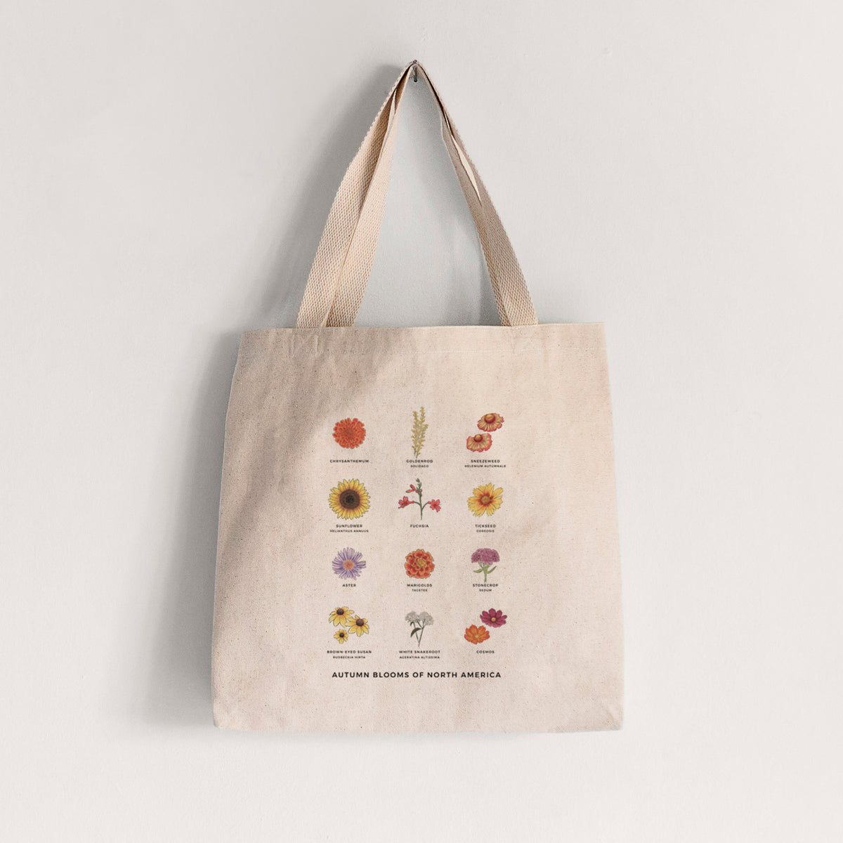 Natural canvas tote bag printed with a full-color chart of autumn flowers, each labeled with its name.