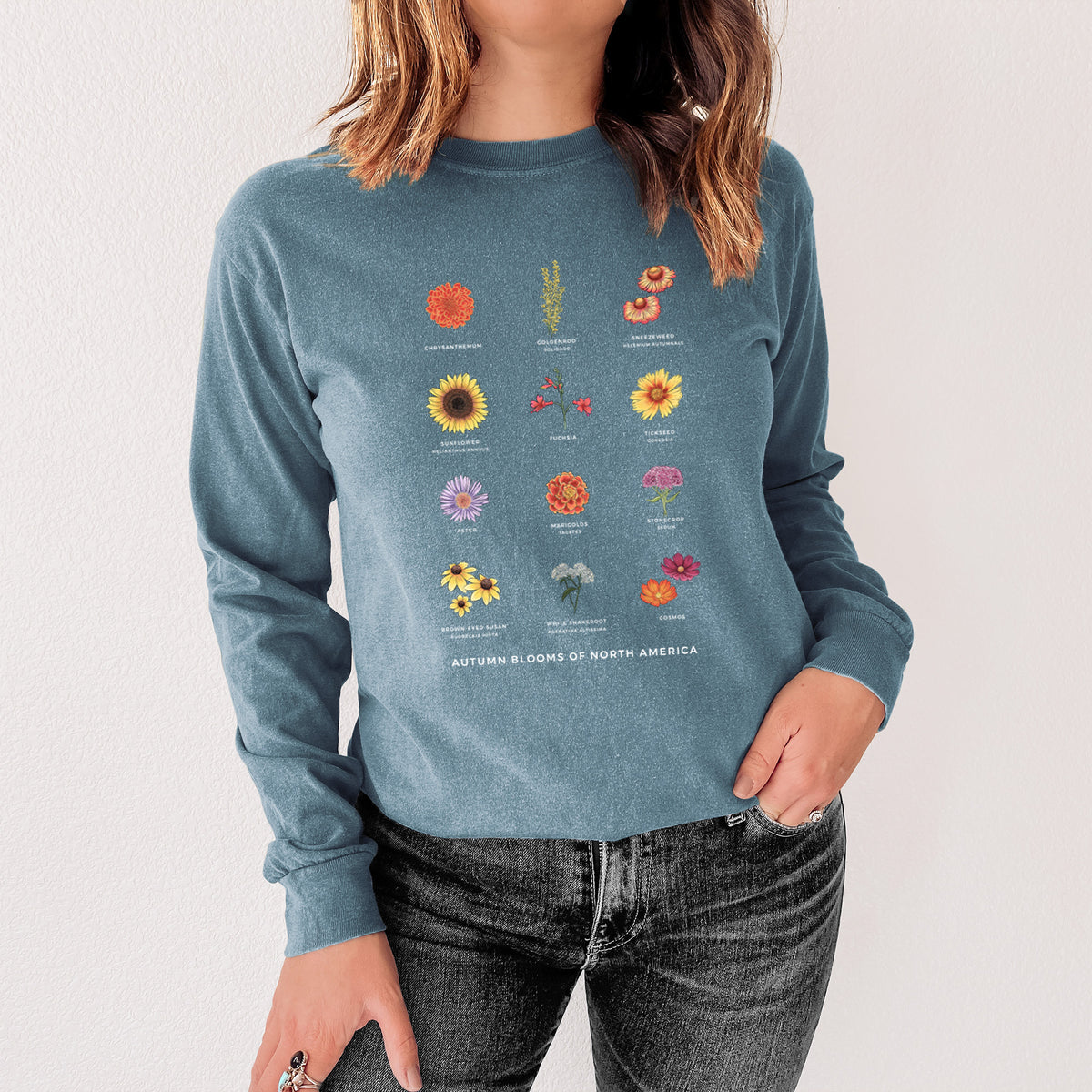 Steel blue Comfort Colors long sleeve shirt printed with a full-color chart of autumn flowers, each labeled with its name, shown in a lifestyle photo.