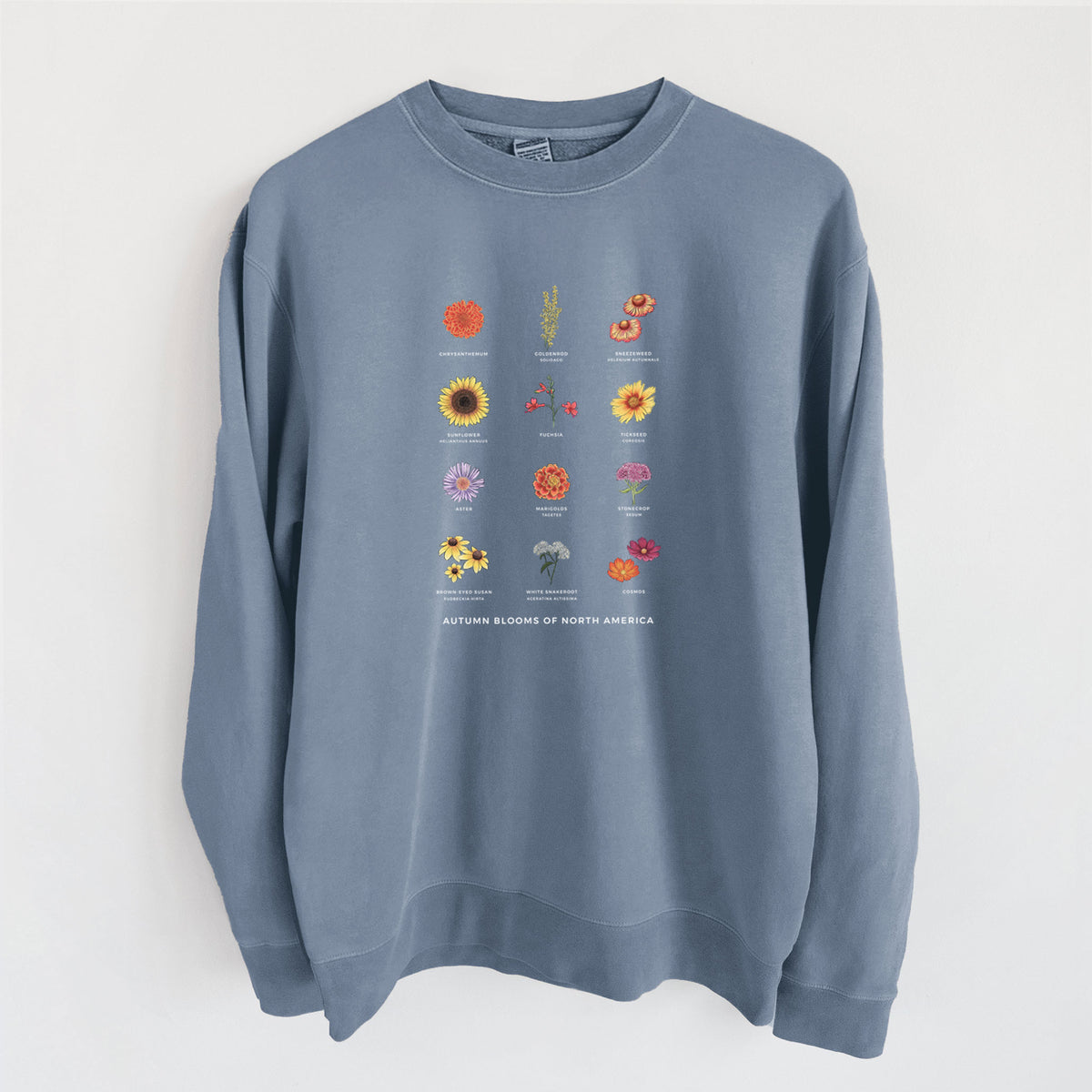 Slate blue pigment dyed crewneck sweatshirt laid flat, printed with a full-color chart of autumn flowers, each labeled with its name.