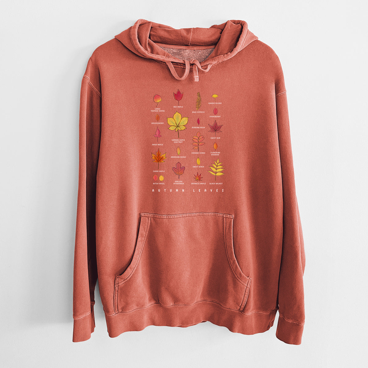 Amber orange pigment dyed hoodie laid flat, printed with a full-color chart of autumn leaves, each labeled with its tree species.
