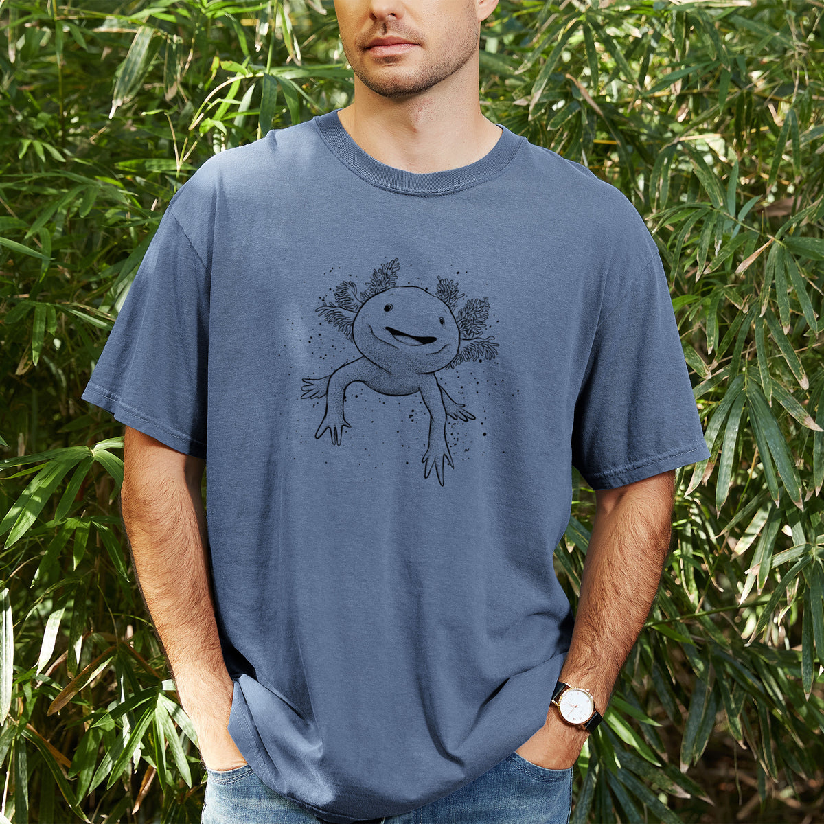 Man wearing a Comfort Colors t-shirt printed with a black ink illustration of a smiling axolotl with feathery gills, outdoors.