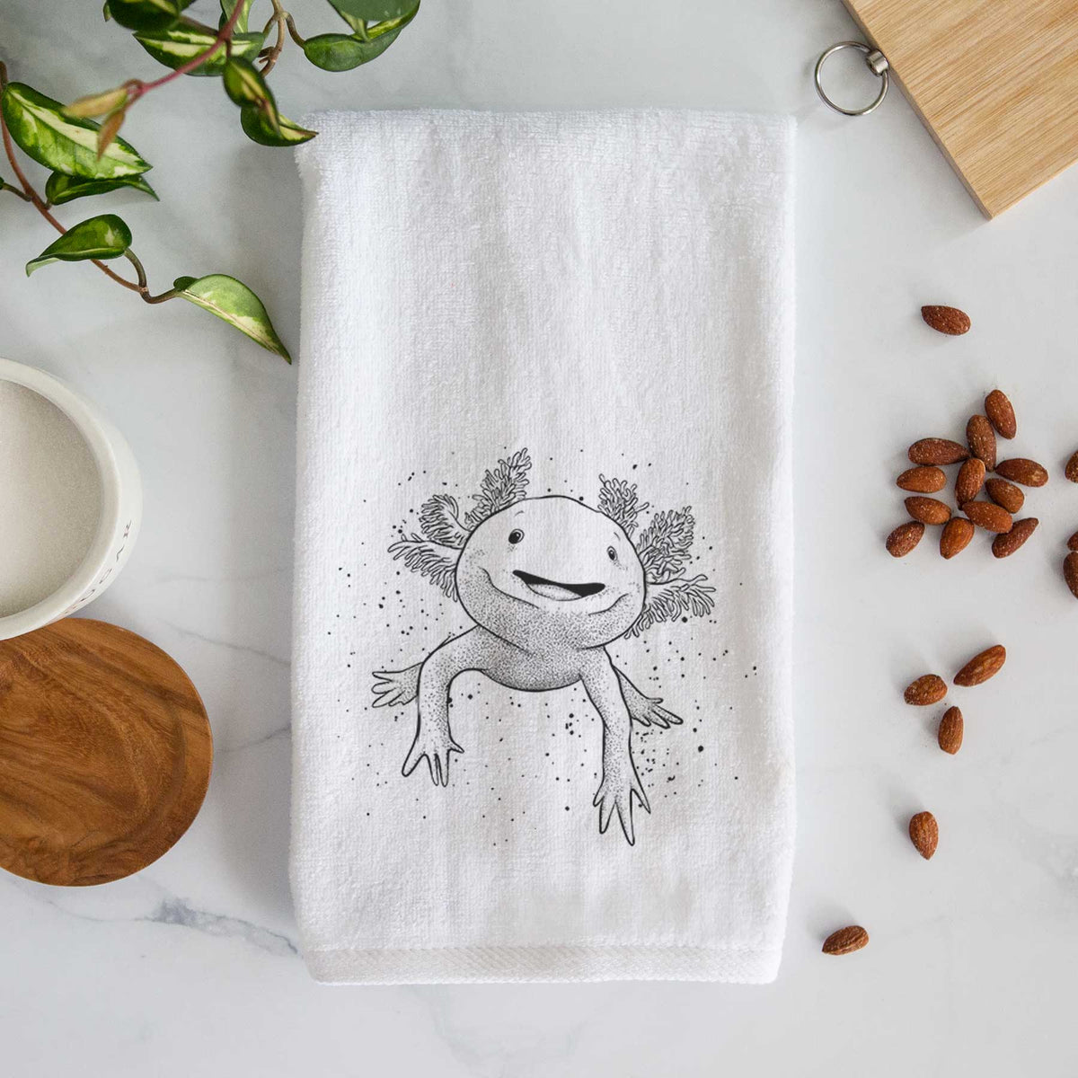White hand towel printed with a black ink illustration of a smiling axolotl with feathery gills.