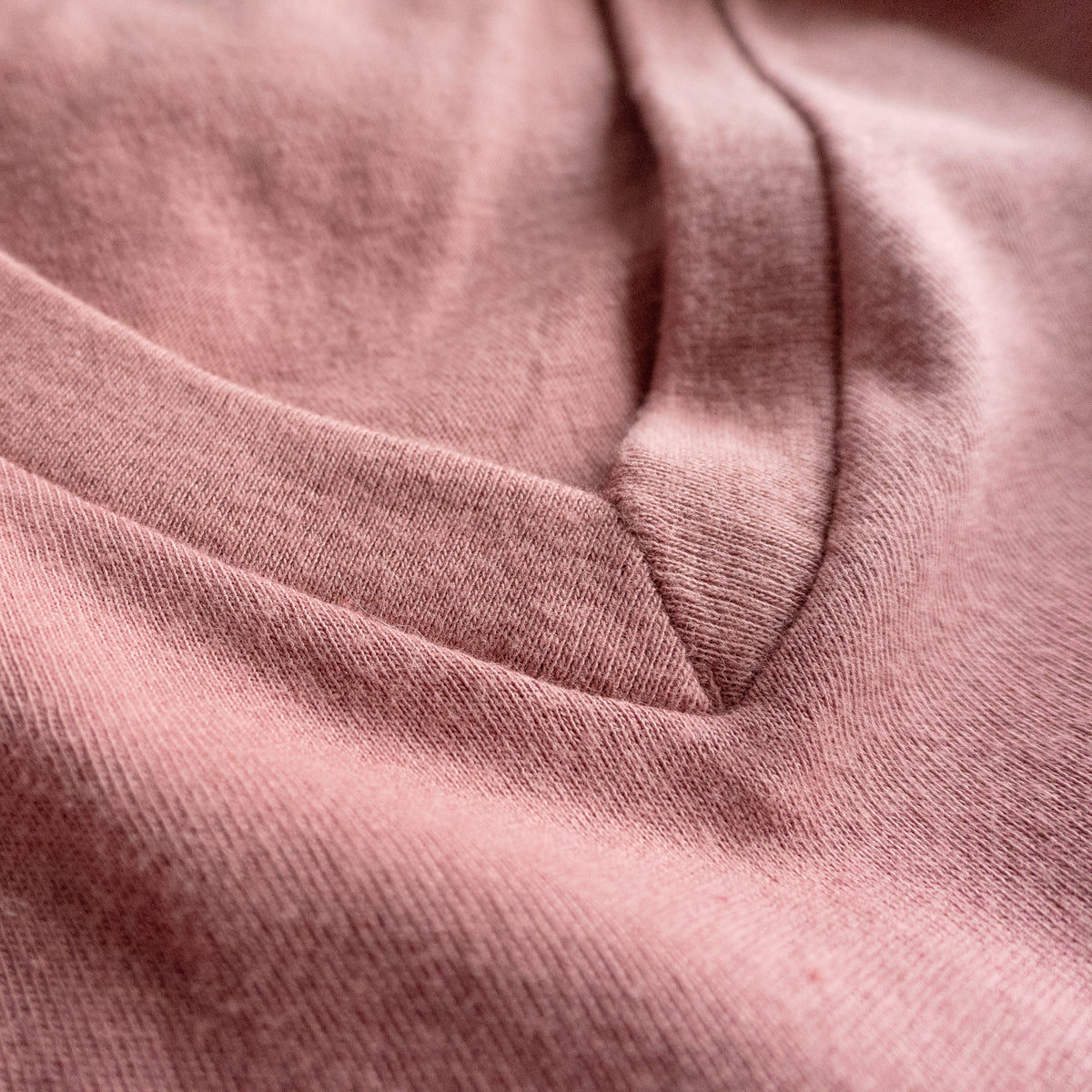 Close-up of the V-neck collar and stitching on a soft pink cotton t-shirt.